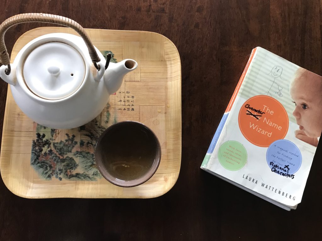 teapot and teacup next to a baby name book, on which the word "baby" is crossed out and replaced with "character"